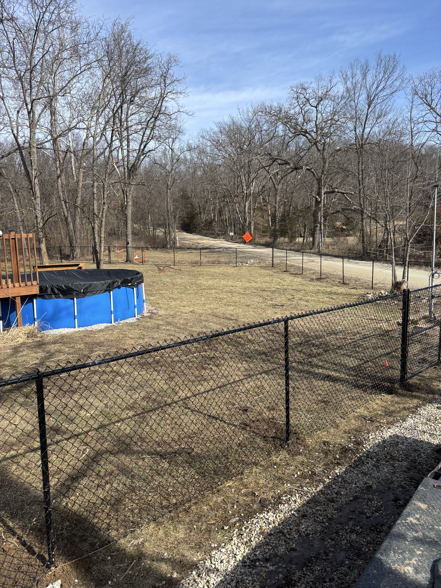 Black chain link fence enclosing rural backyard with pool